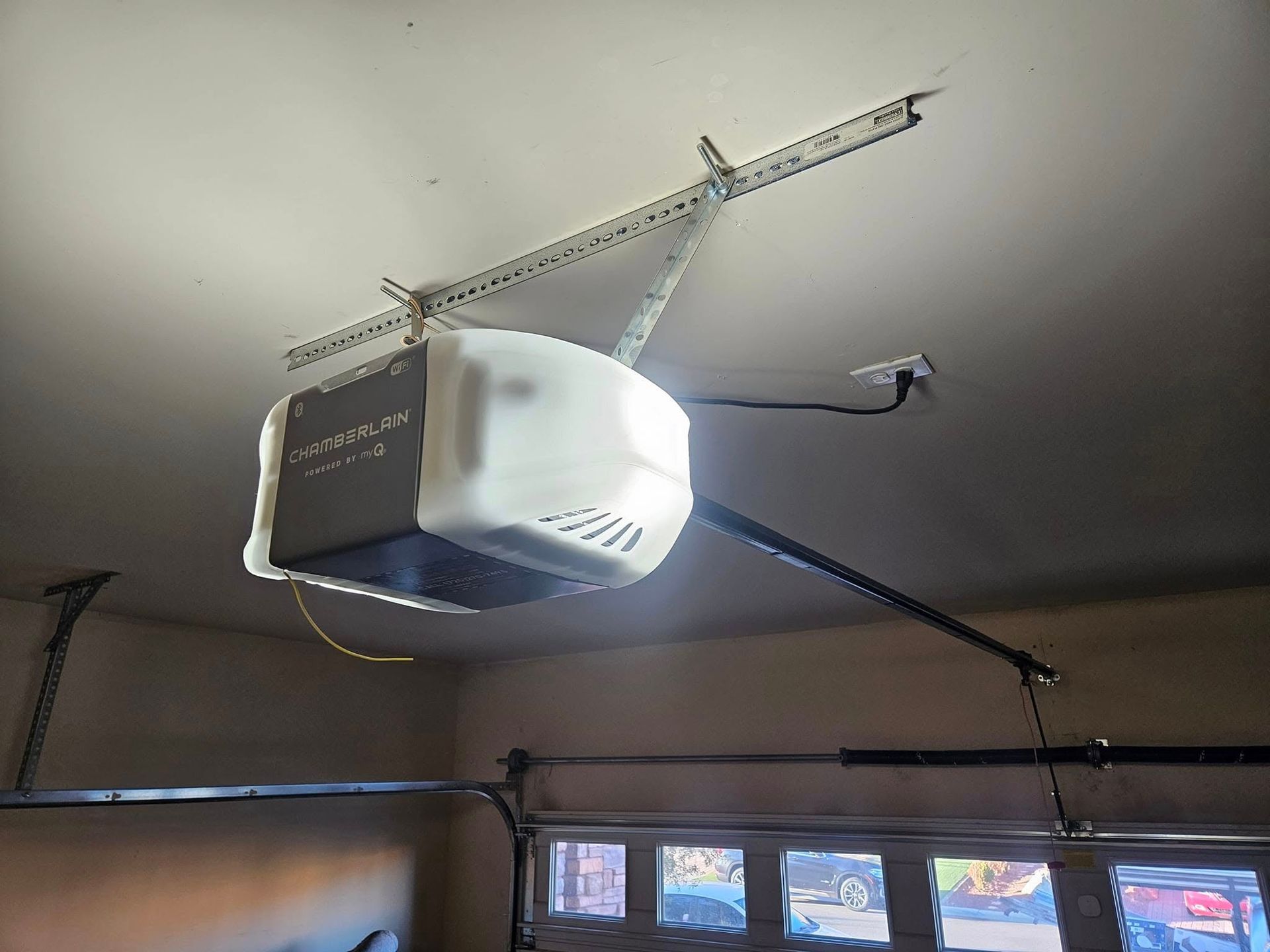 A garage door opener is hanging from the ceiling of a garage.