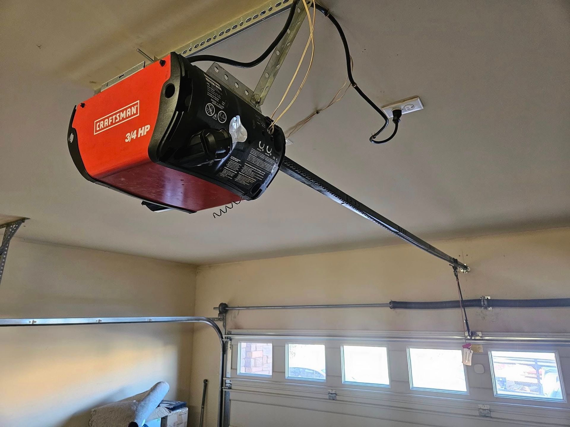 A garage door opener is hanging from the ceiling in a garage.