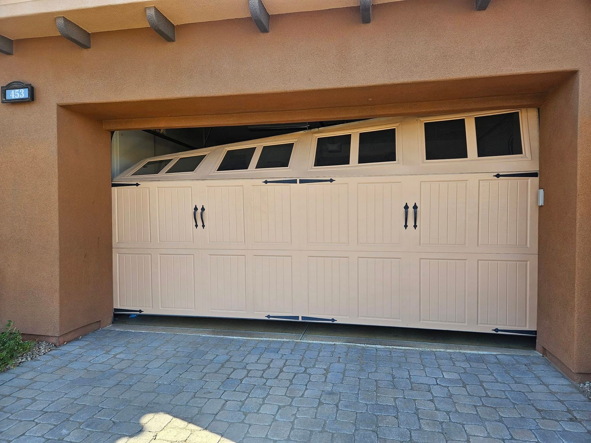 A tan garage door that is open and broken