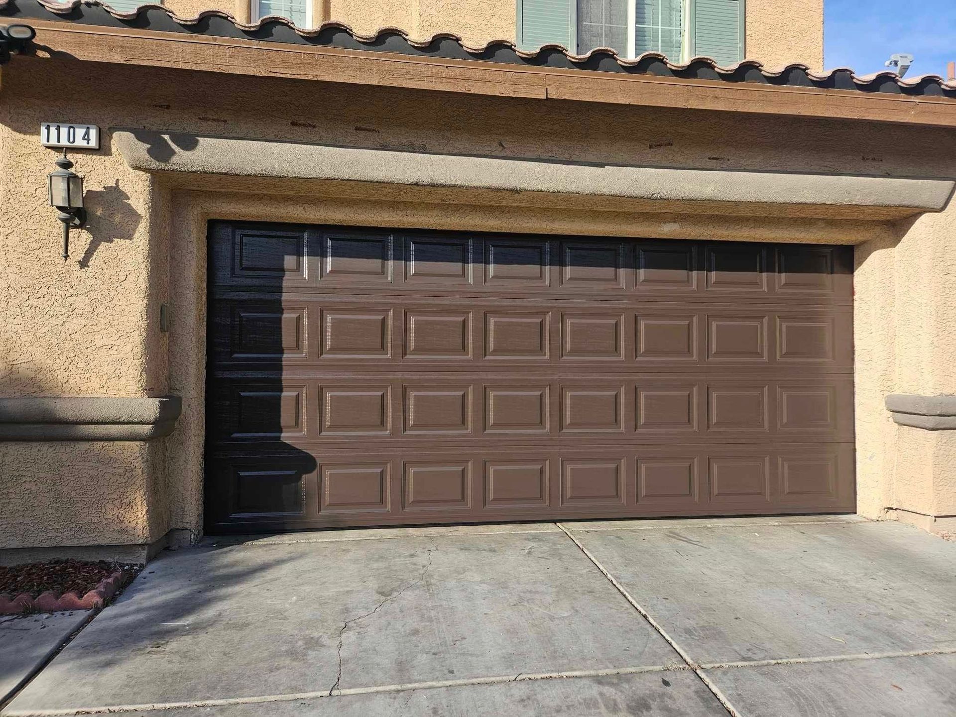 A brown garage door is open in front of a house.