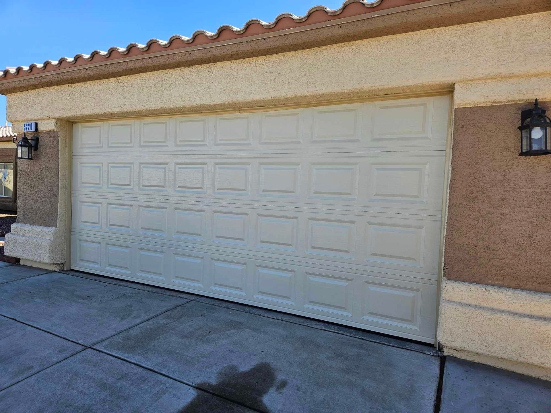A white garage door is sitting on the side of a house.