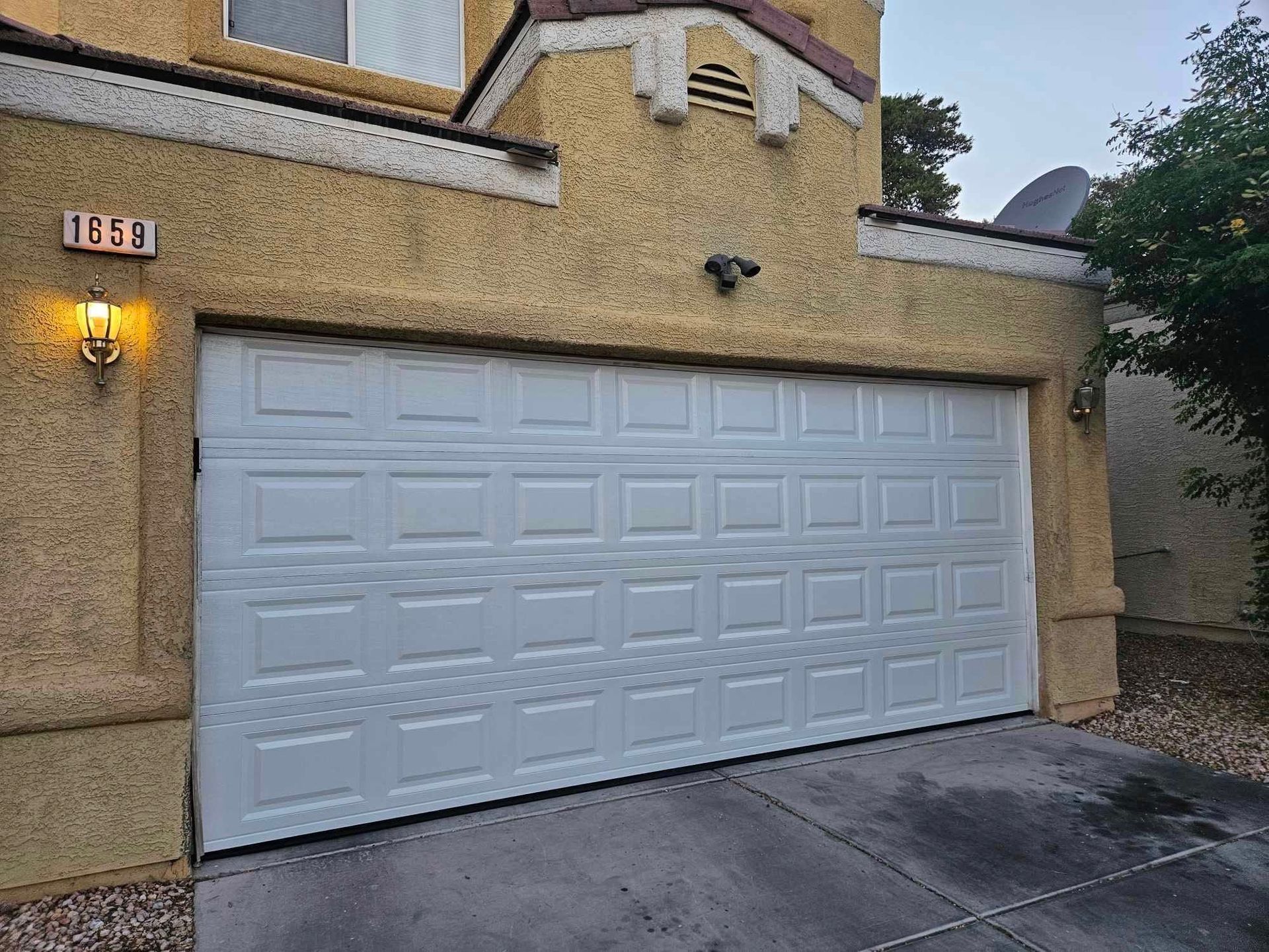 A white garage door is open in front of a house.