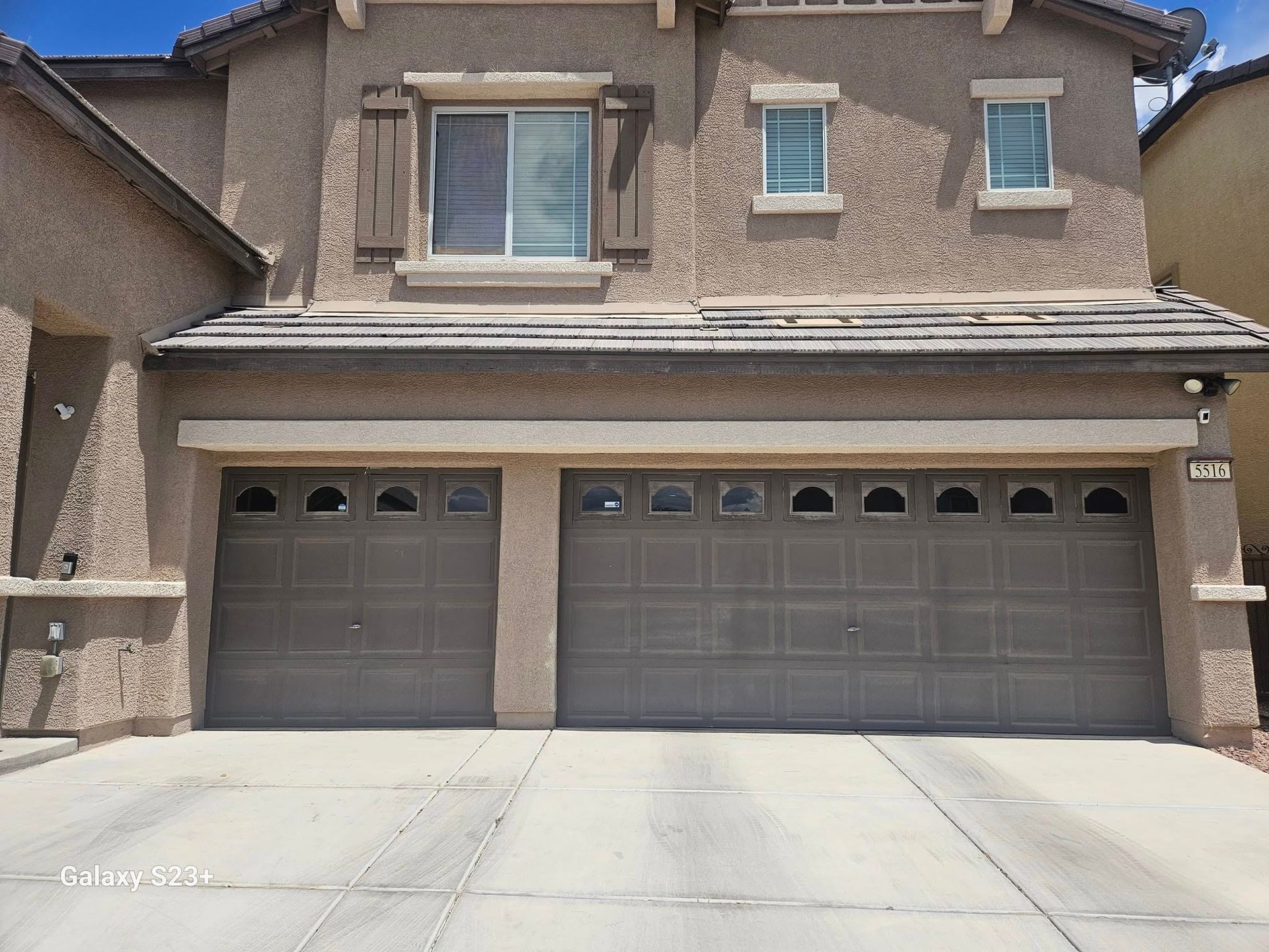 A large house with two garage doors and a driveway