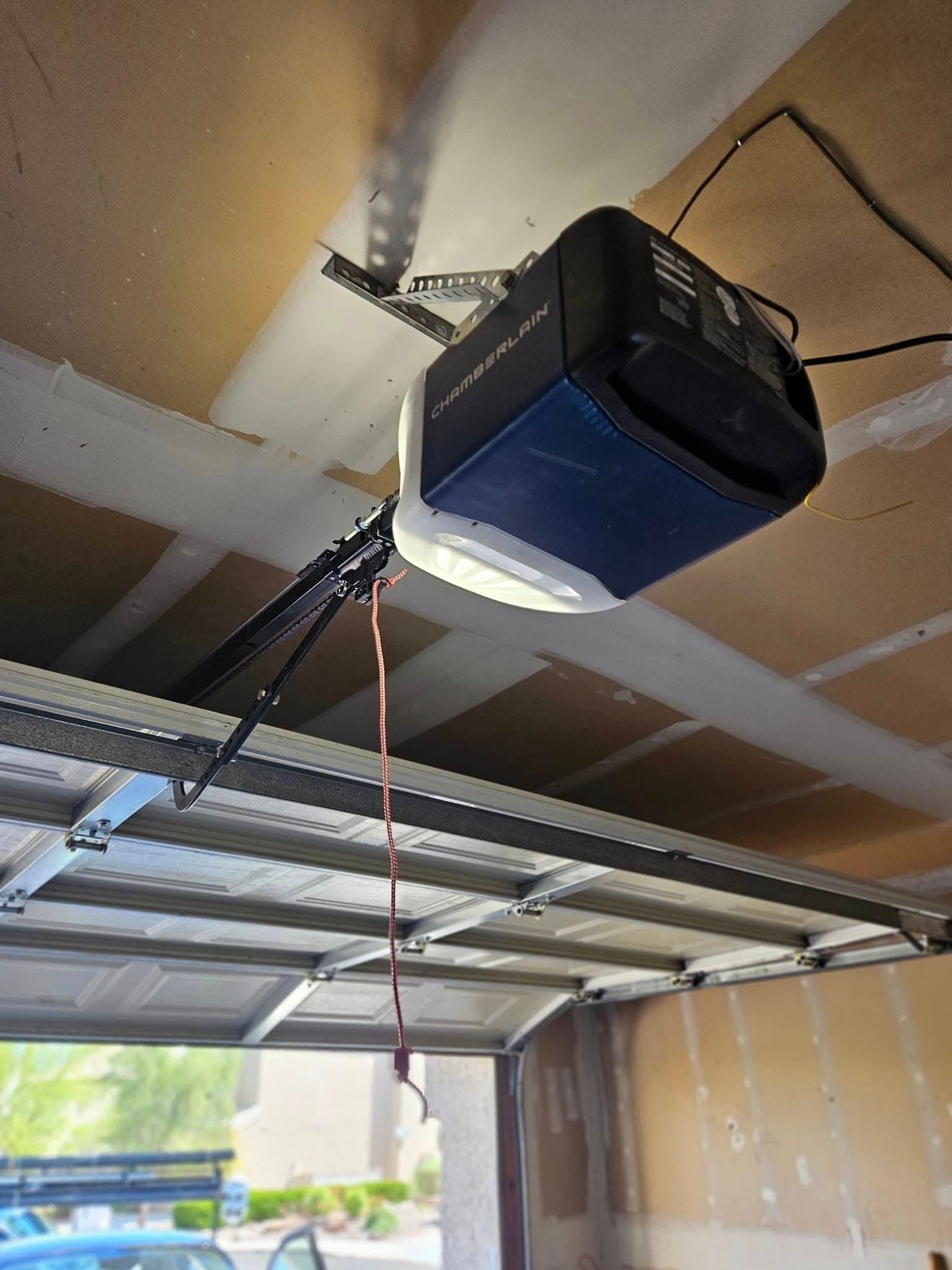 A garage door opener is hanging from the ceiling of a garage.