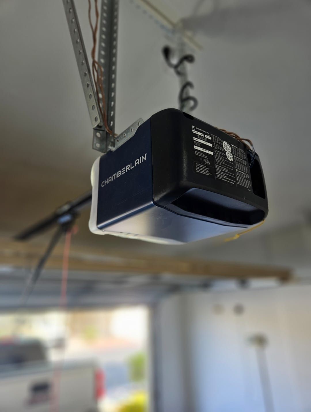 A garage door opener is hanging from the ceiling of a garage.