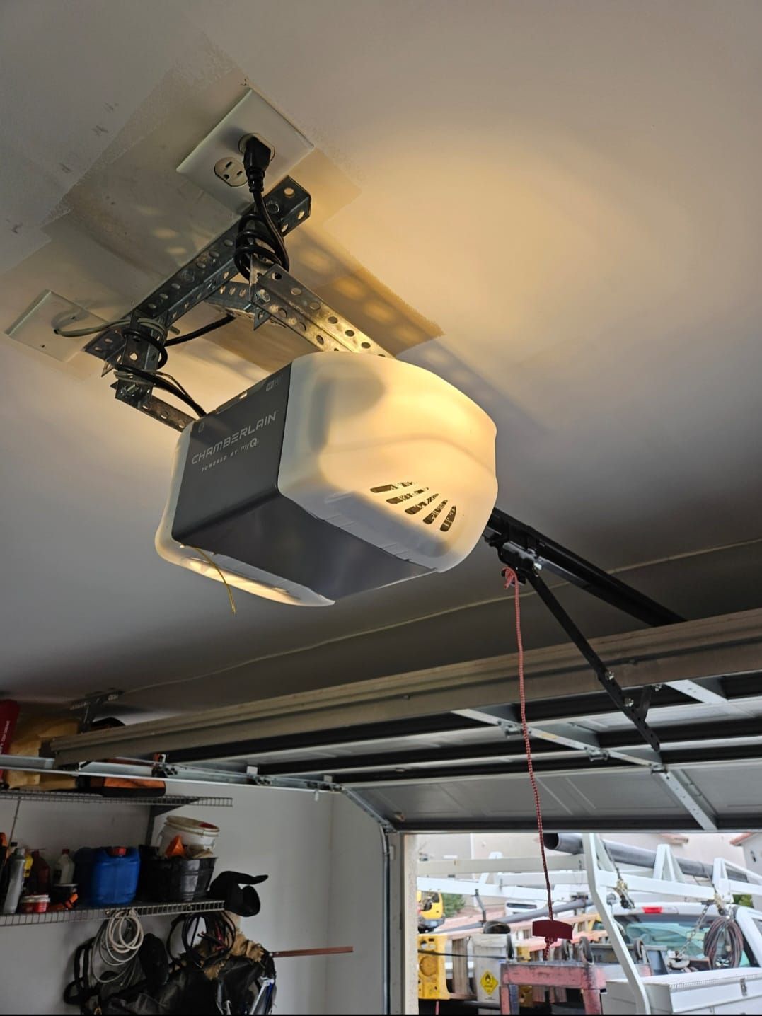 A garage door opener is hanging from the ceiling of a garage.
