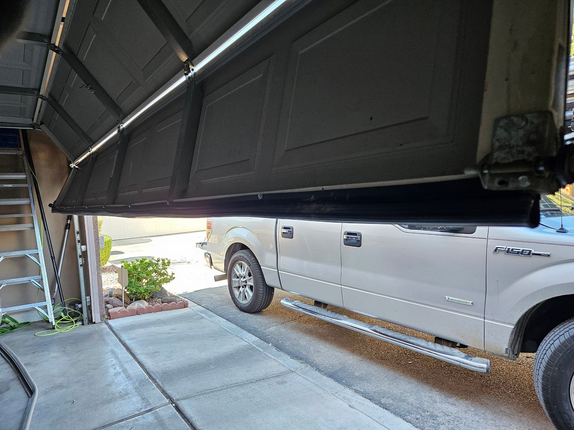 A white truck is parked in a garage with the door open.