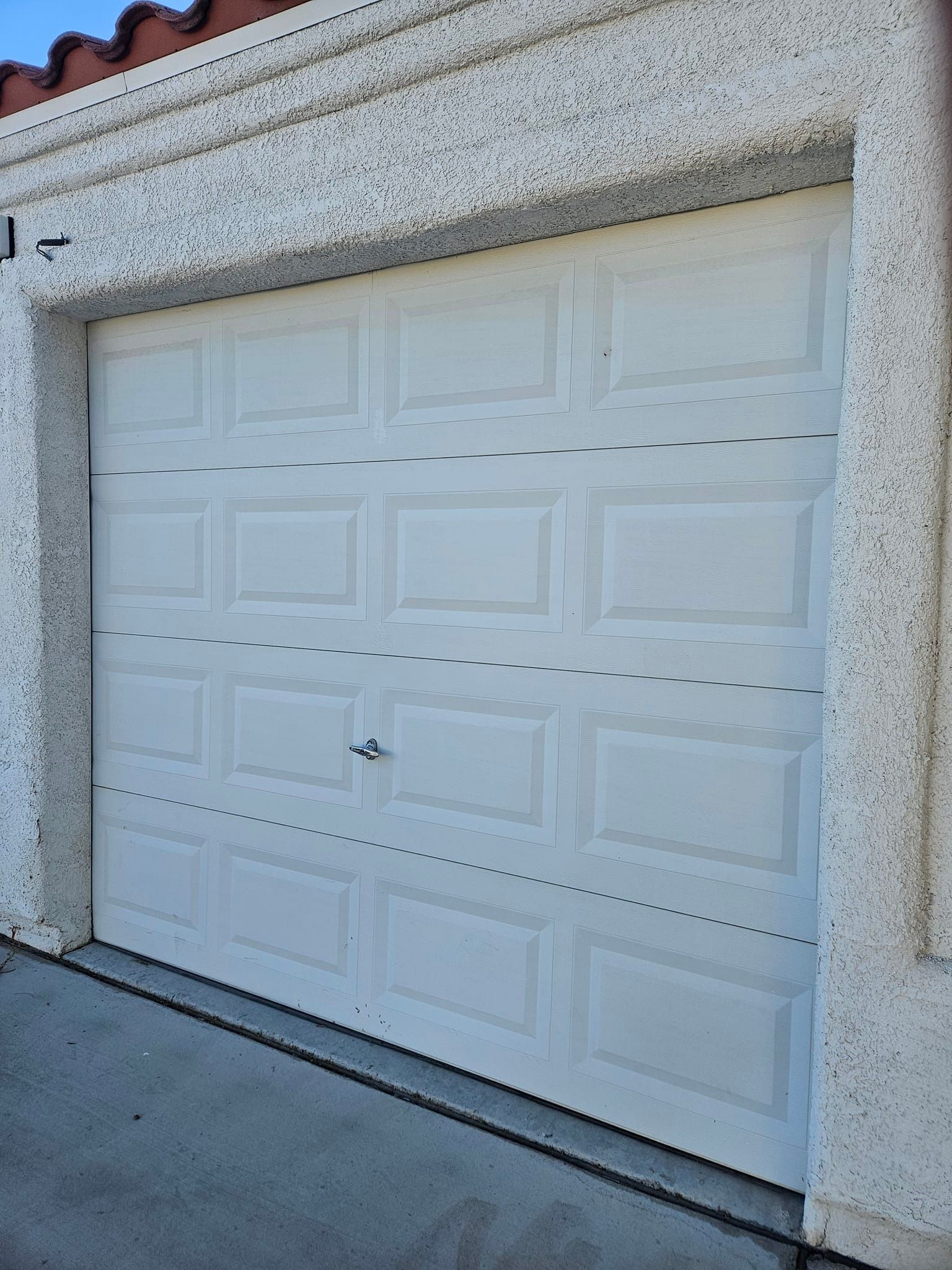 A white garage door is sitting on the side of a building.
