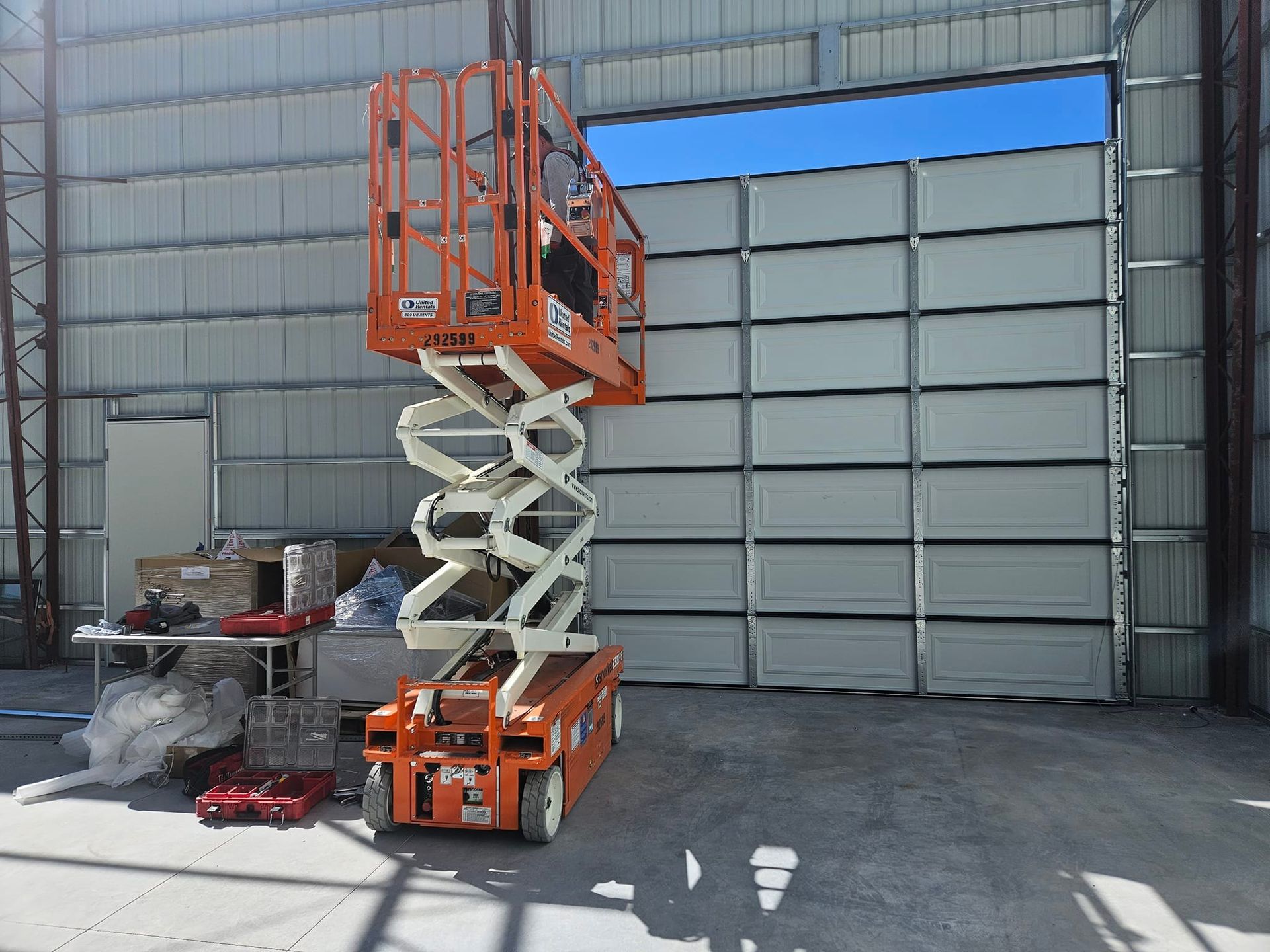 A scissor lift is sitting in front of a building