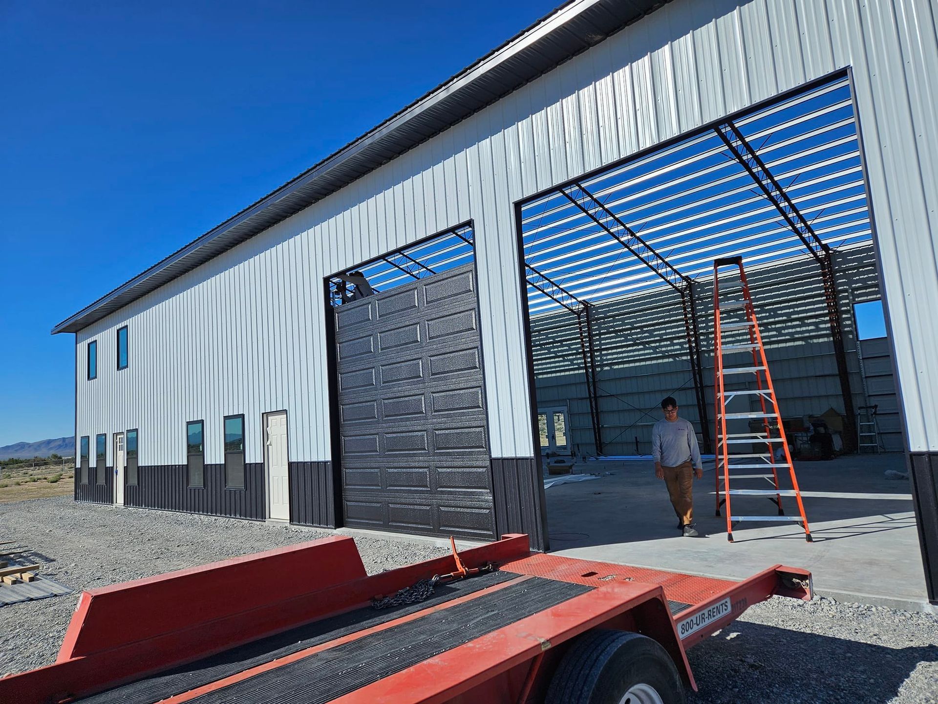 A man is standing in front of a building with a trailer in front of it.