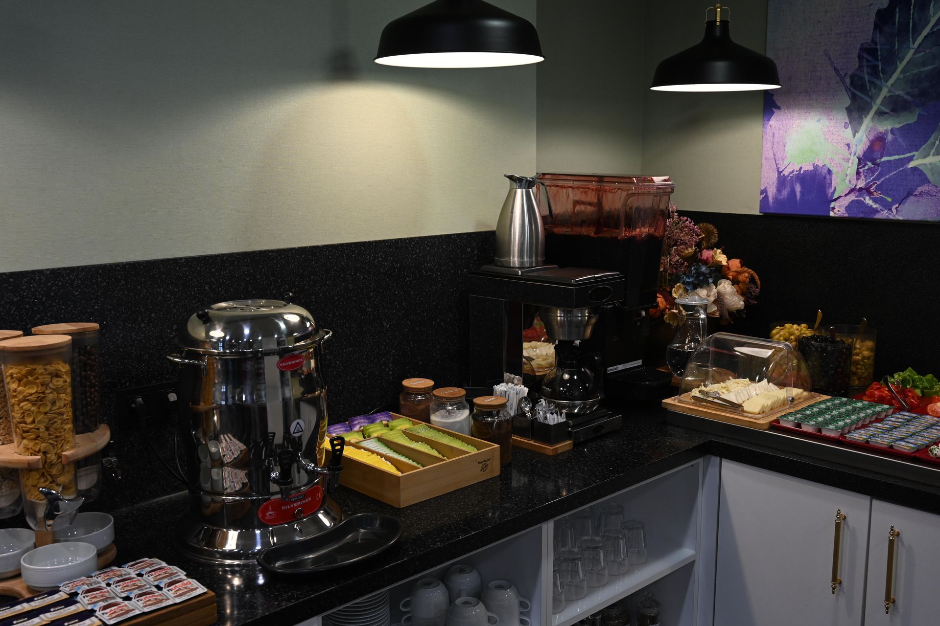 A buffet with various foods like fruit, bread, and cheese, set up on a counter with overhead lighting.