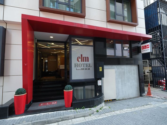 The entrance to the Elm Hotel in Seoul, South Korea, featuring a red canopy, black steps, and potted plants.