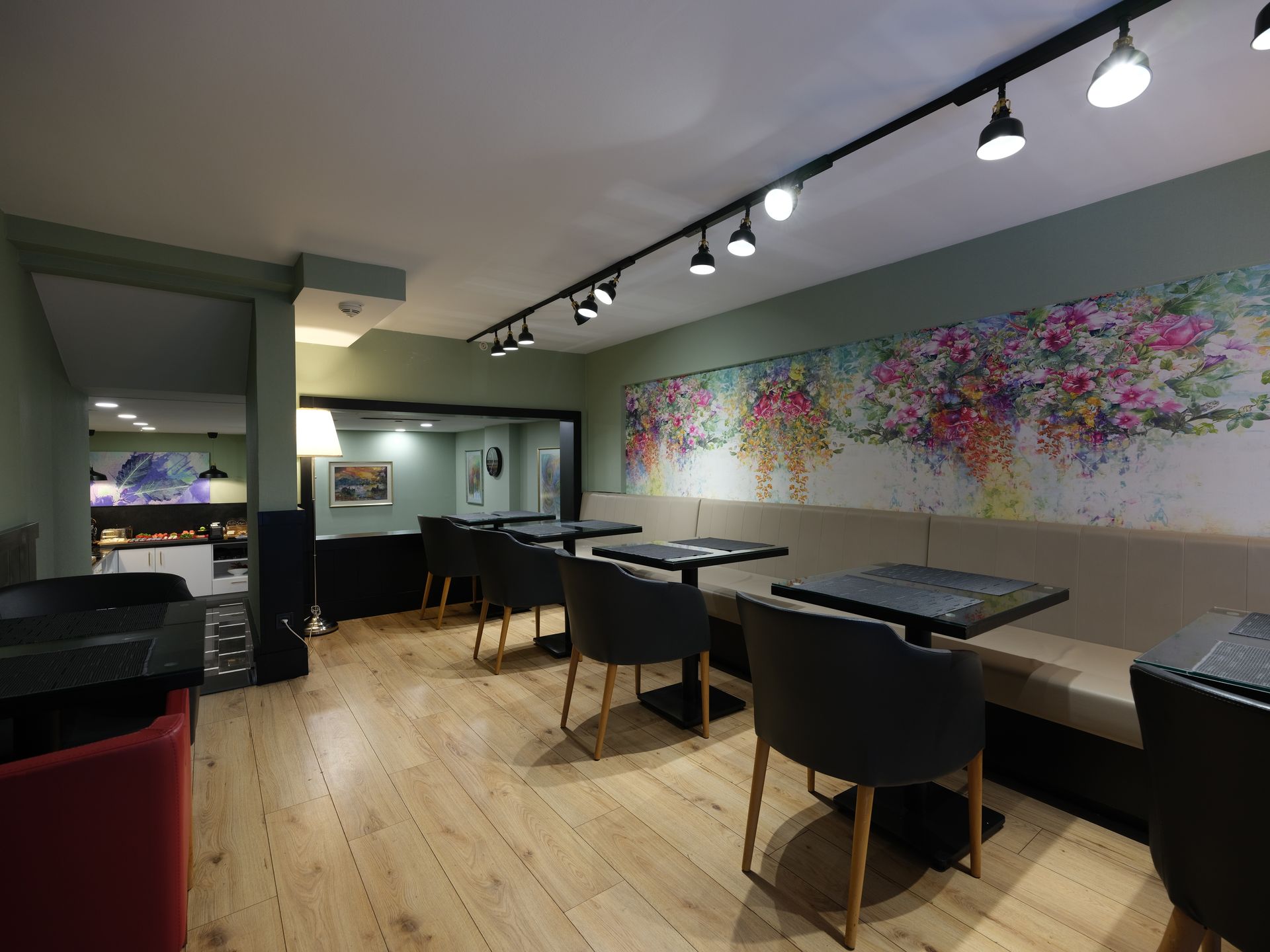 An interior shot of a cafe with tables, chairs, and a floral mural on the wall. 