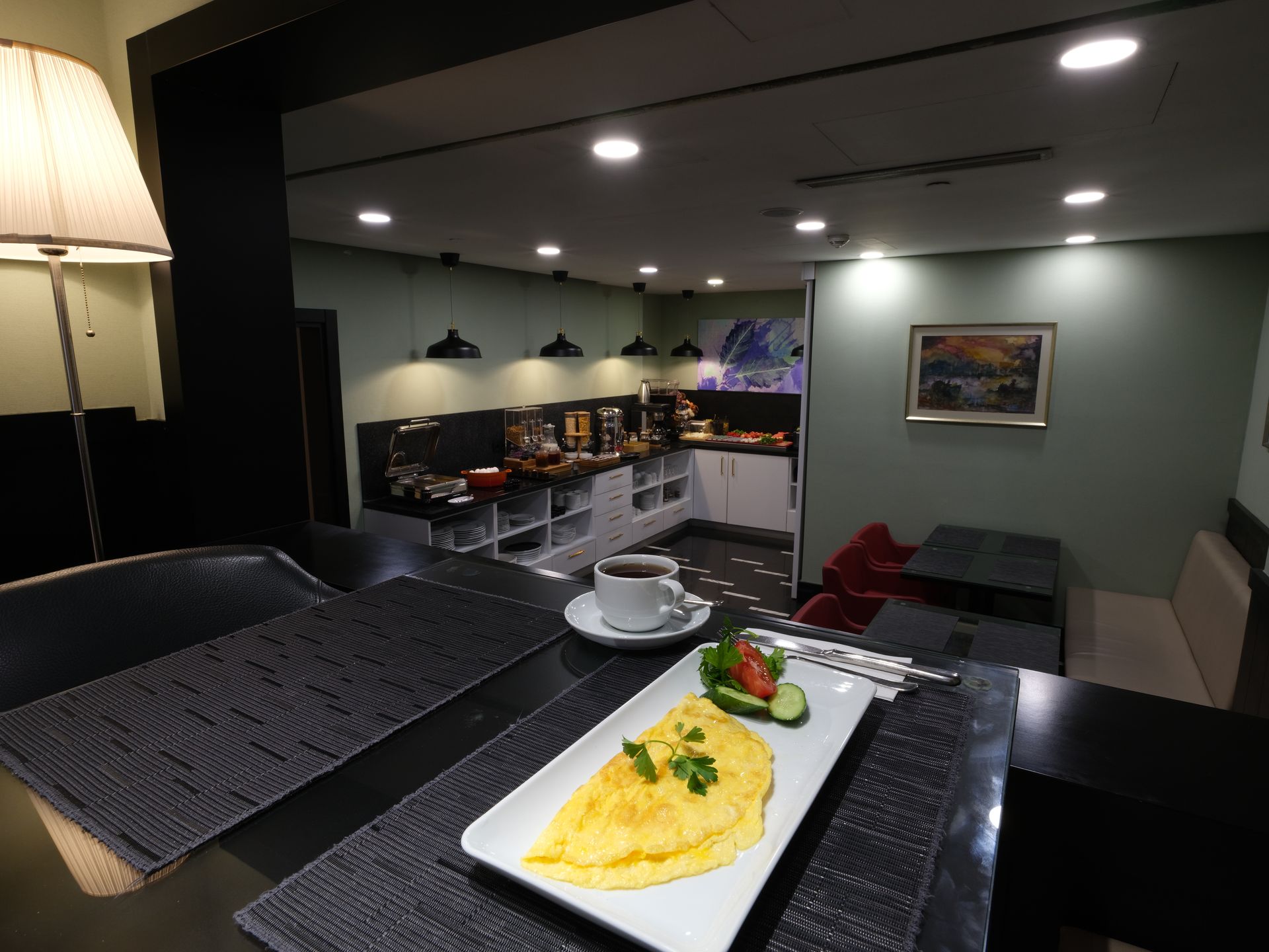 Breakfast bar with omelet, coffee, and buffet in the background.  Gray and black decor with green accent wall.