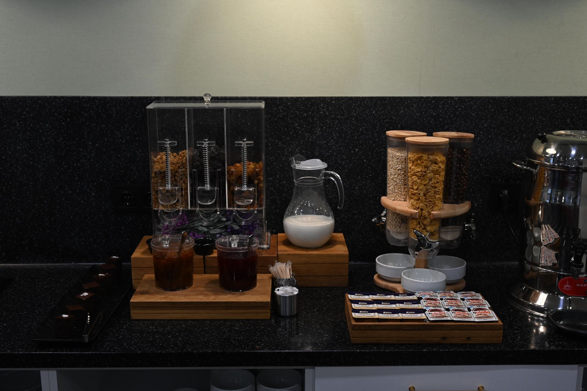 Cereal dispenser and breakfast station on a countertop, with milk, juice, and cereal options.