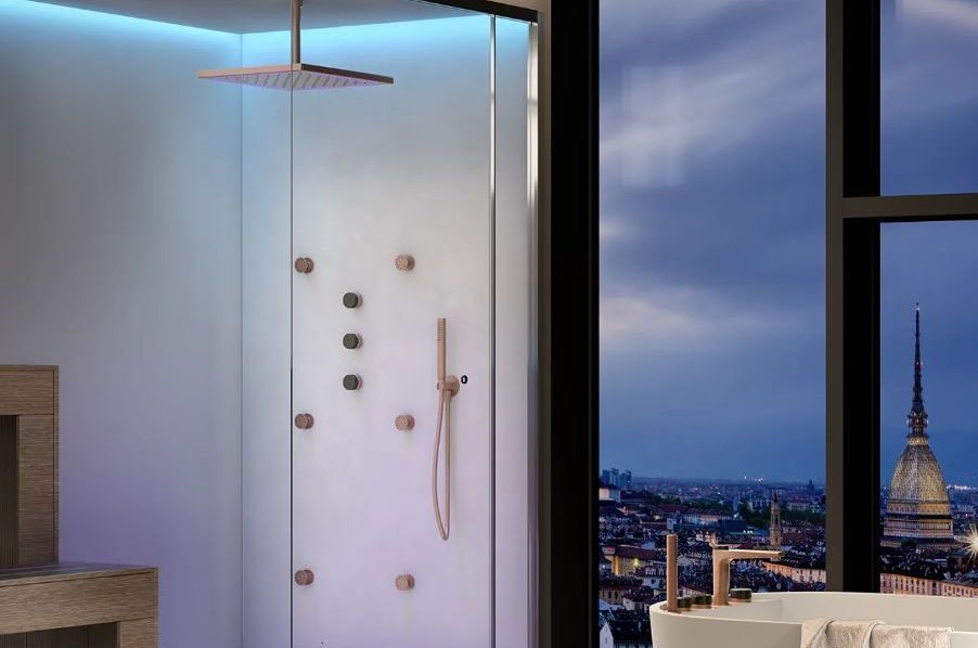 Una moderna cabina doccia in vetro con rubinetteria metallica è situata accanto a una finestra che si affaccia sulla Mole Antonelliana di Torino.