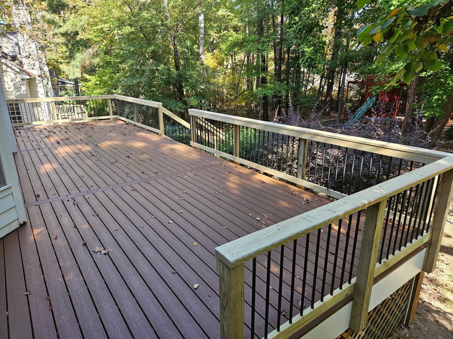 Composite deck off a sliding glass door with black aluminum balusters and lattice skirting