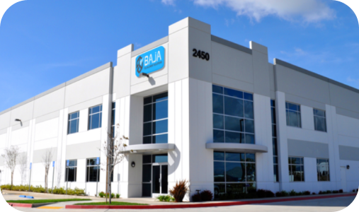 Modern white-and-gray office building with blue windows and a blue logo under a clear sky