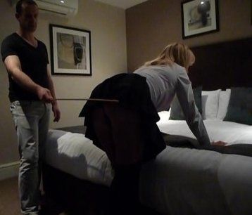 Mature male disciplinarian administering the cane to a female client