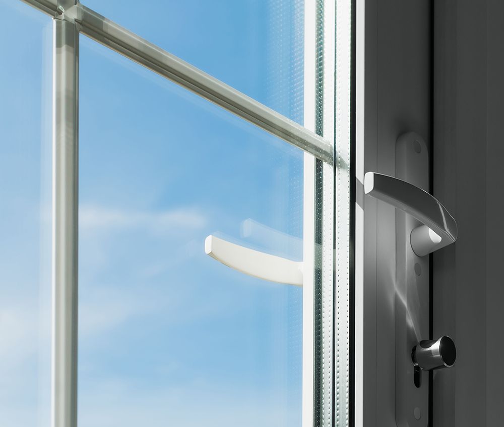 White window frame with a handle, open, against a blue sky.