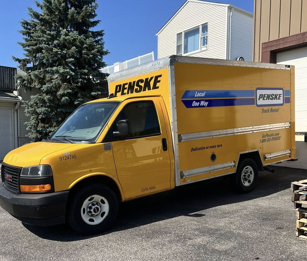 Yellow Penske GMC box truck parked outside.