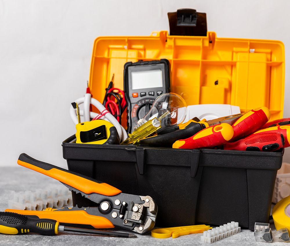 Yellow toolbox open with various tools: multimeter, wire strippers, screwdrivers, and more.