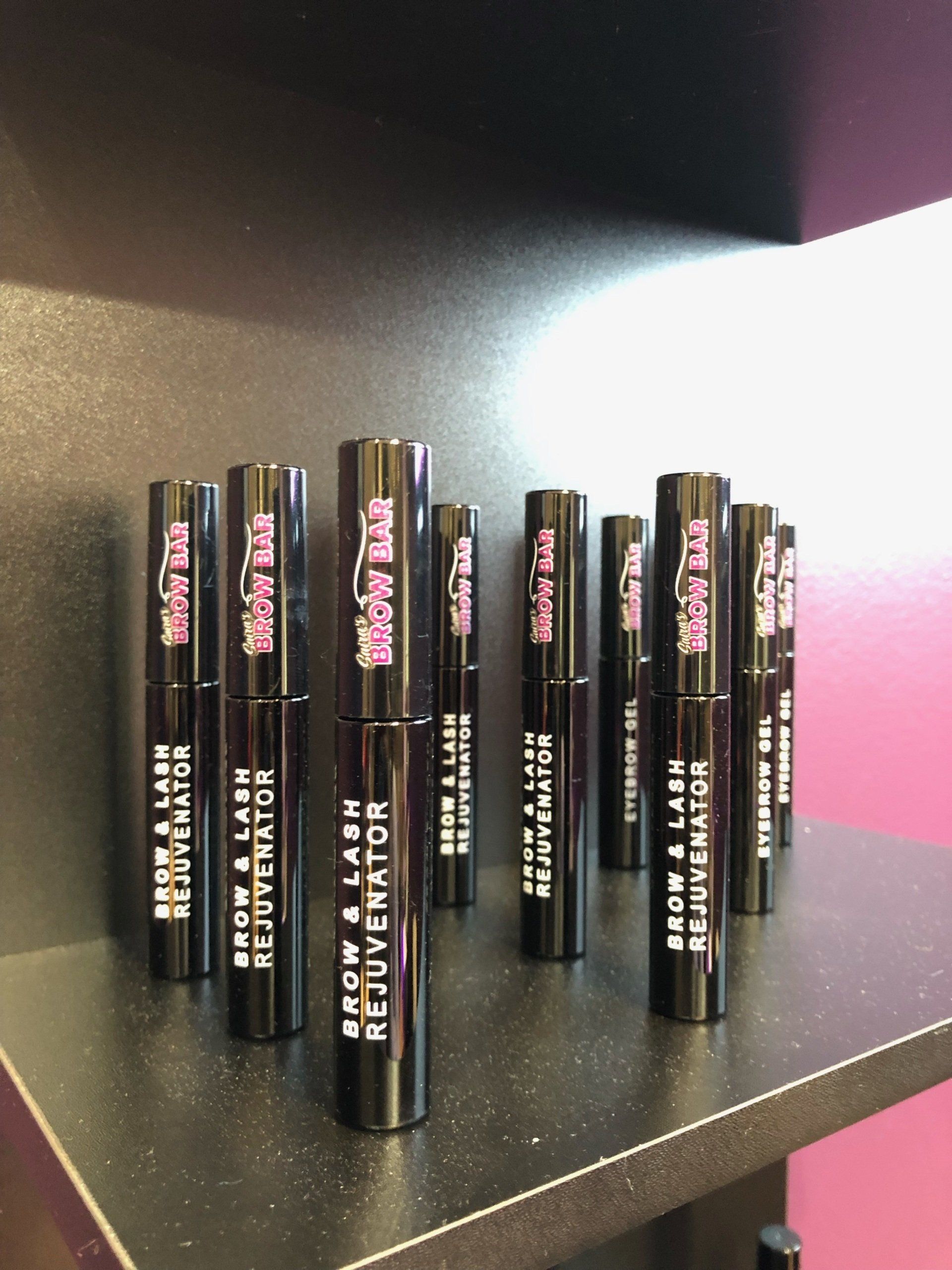 Several bottles of brow and lash rejuvenator are lined up on a shelf