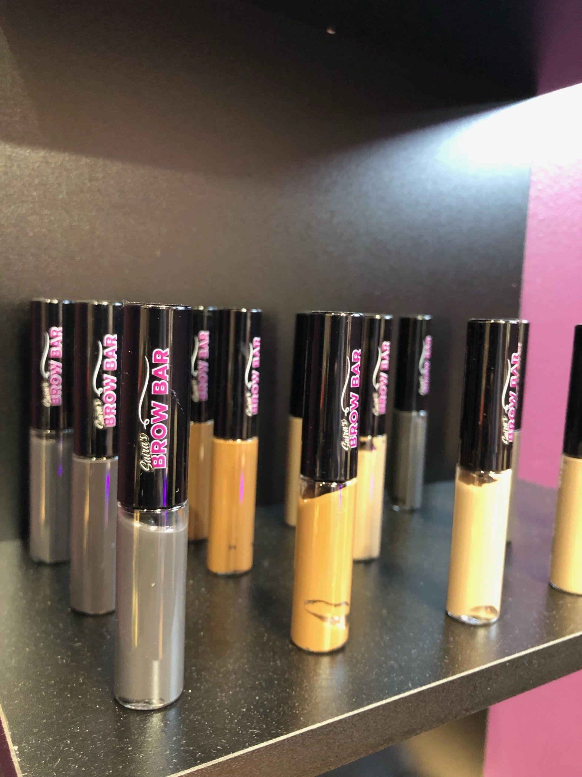 Several bottles of makeup are lined up on a shelf