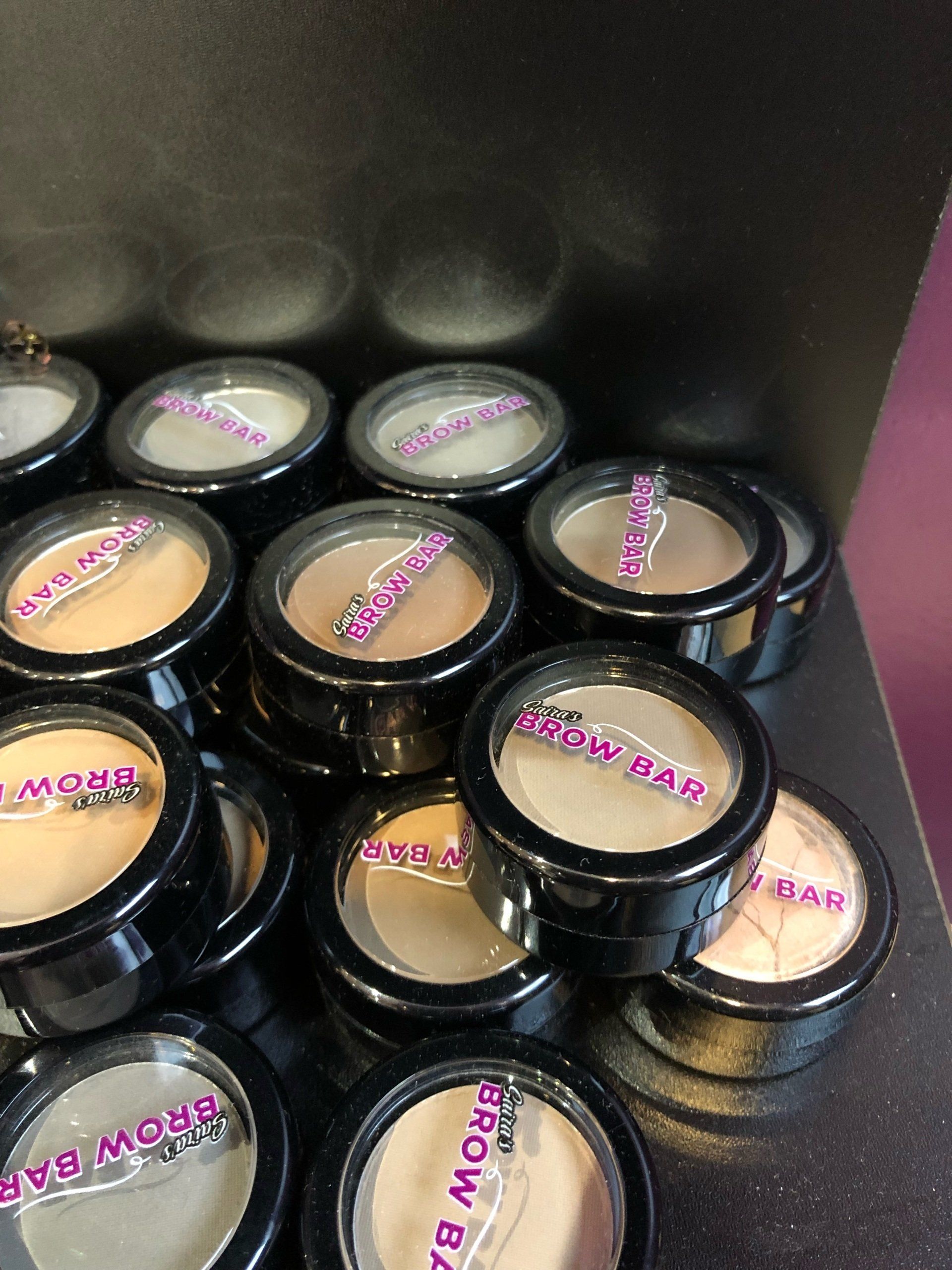 A bunch of makeup containers with the word brow bar on them