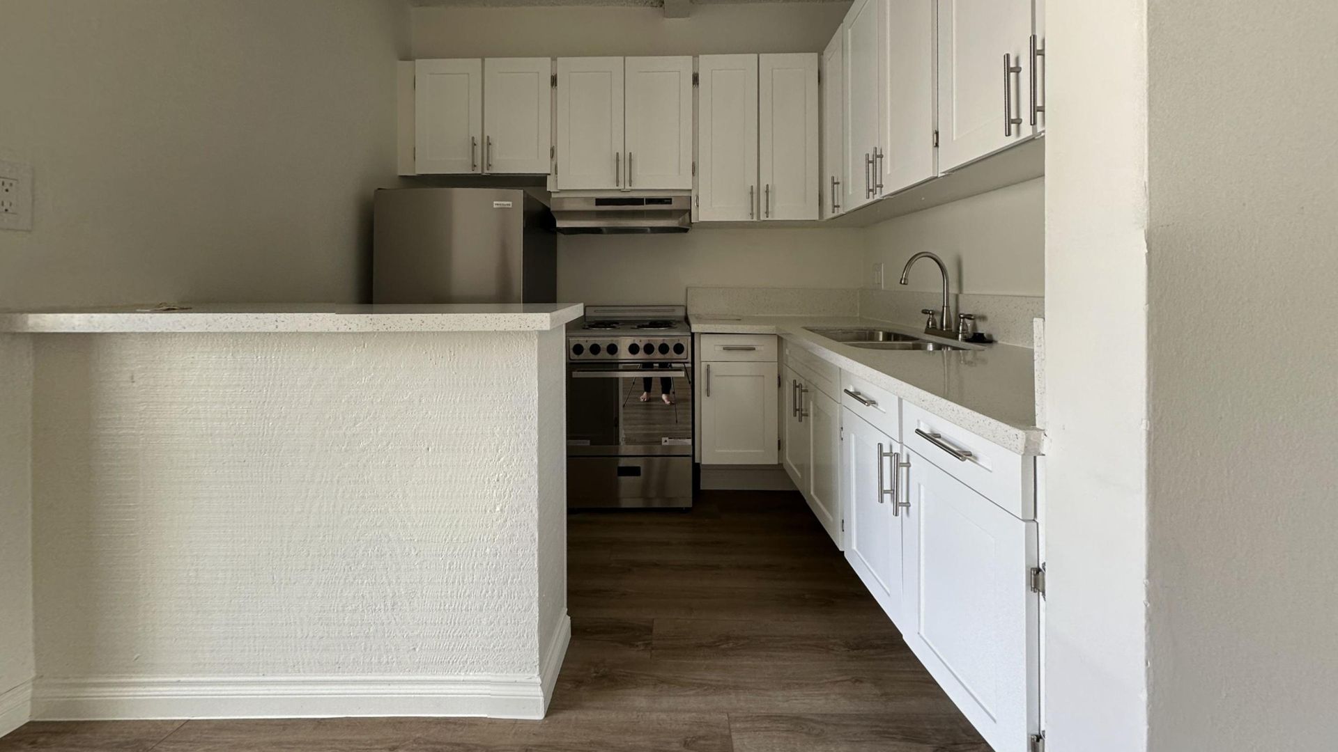 Small kitchen with white cabinets, stainless steel appliances, and a breakfast bar.