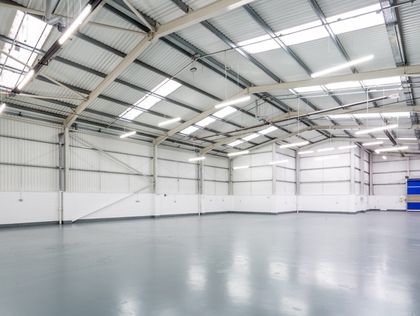 Empty warehouse interior with gray floors and white walls and metal roof.