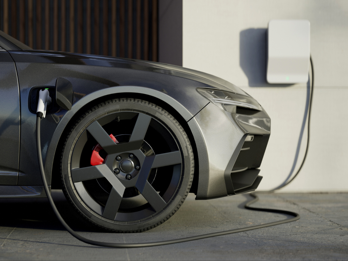 Gray electric car charging from a wall-mounted white charger.