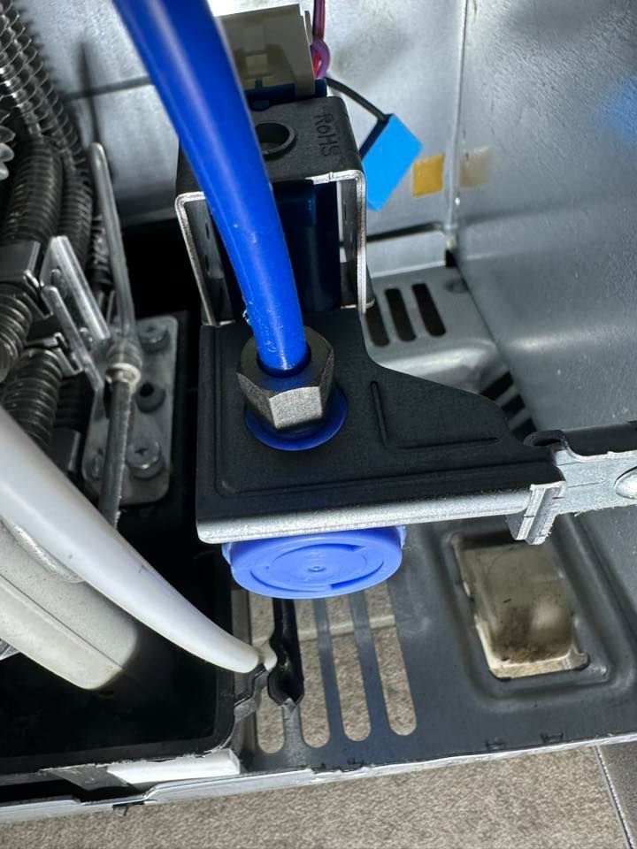A blue pipe is attached to a metal bracket on a machine
