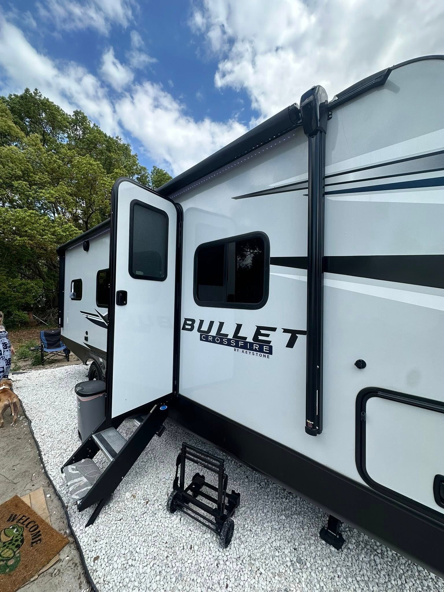 A white rv with the door open is parked in a gravel lot.