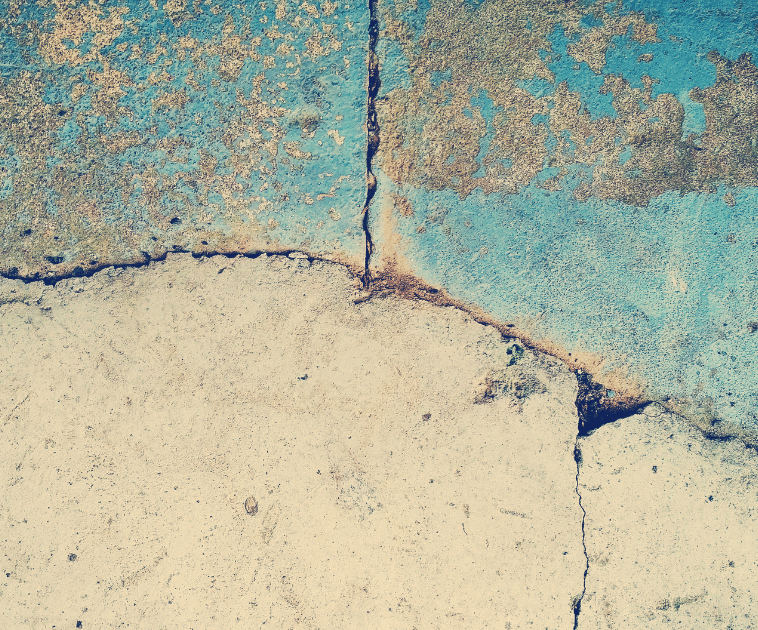 An image of a worker pouring asphalt on the cracked concrete driveway.