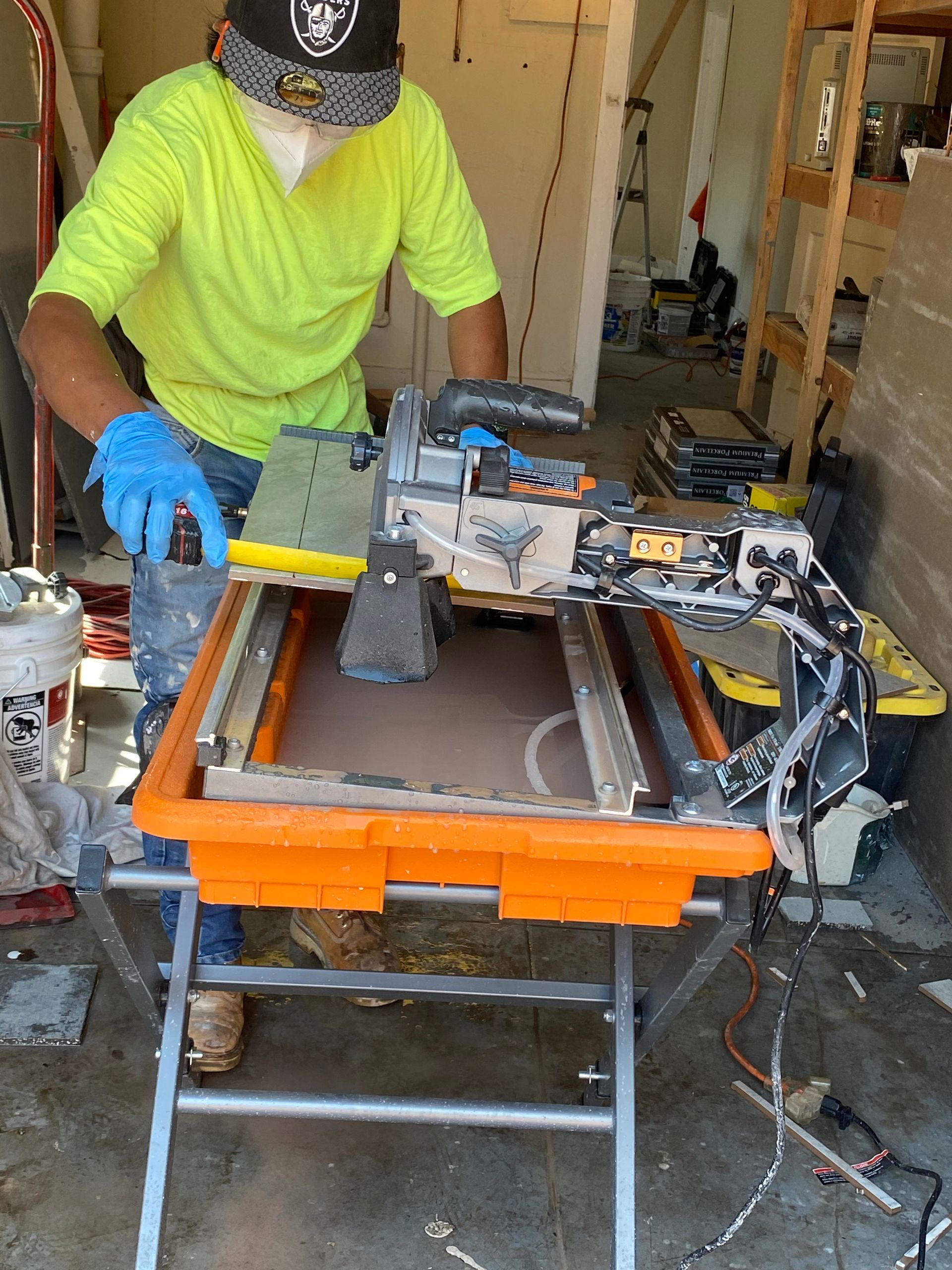A man is working on a tile saw in a garage