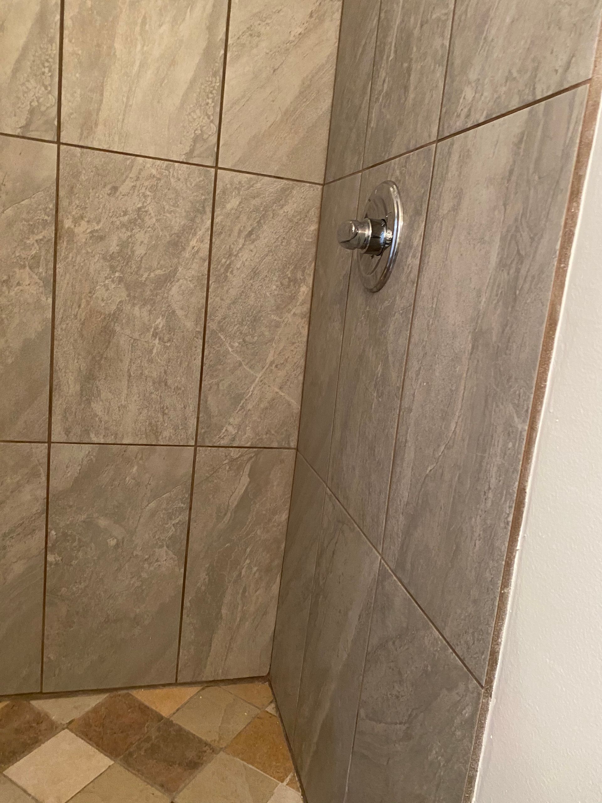 A bathroom with tiled walls and a shower head.