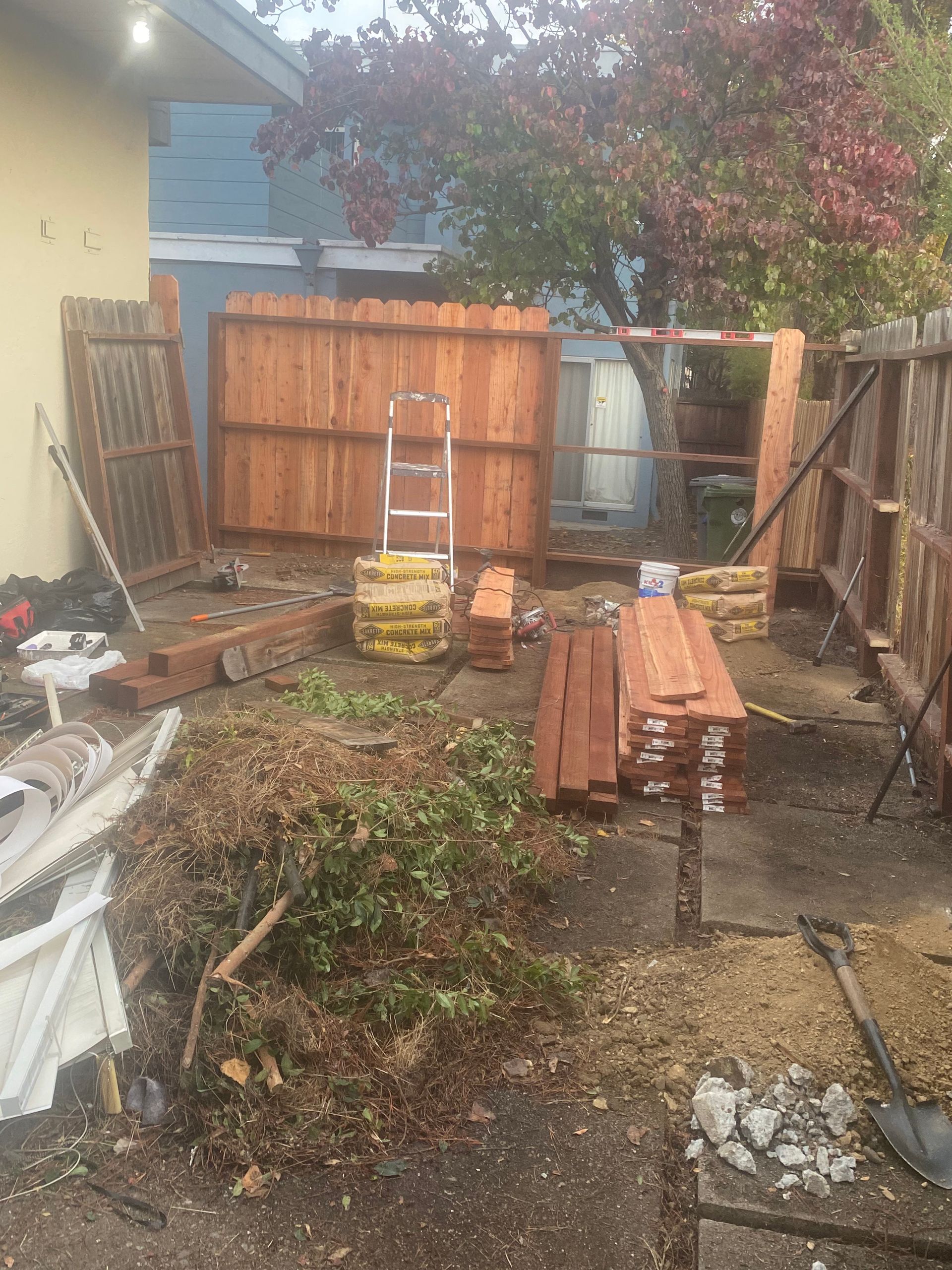 A wooden fence is being built in the backyard of a house.