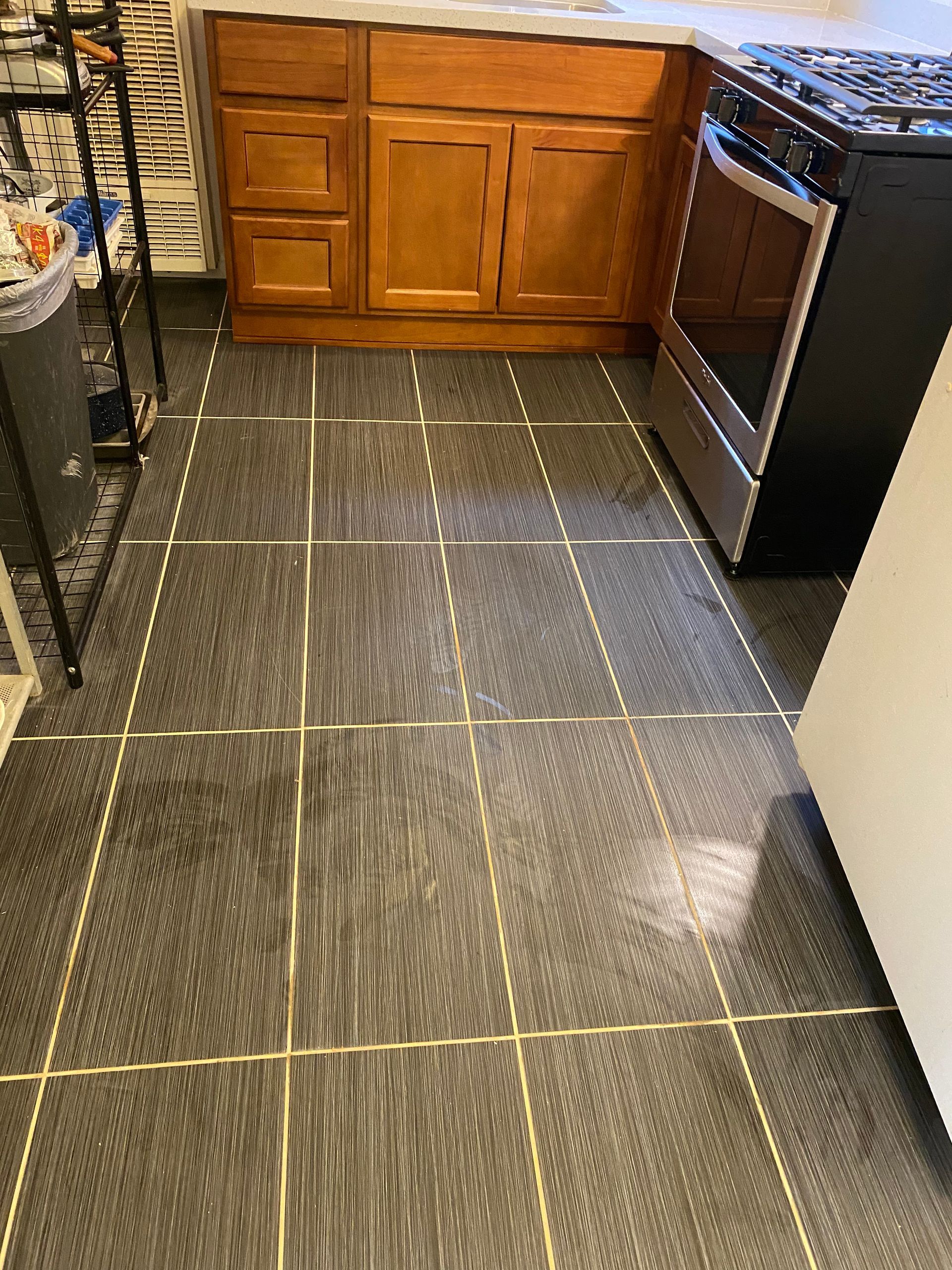 A kitchen with a black tile floor and wooden cabinets.