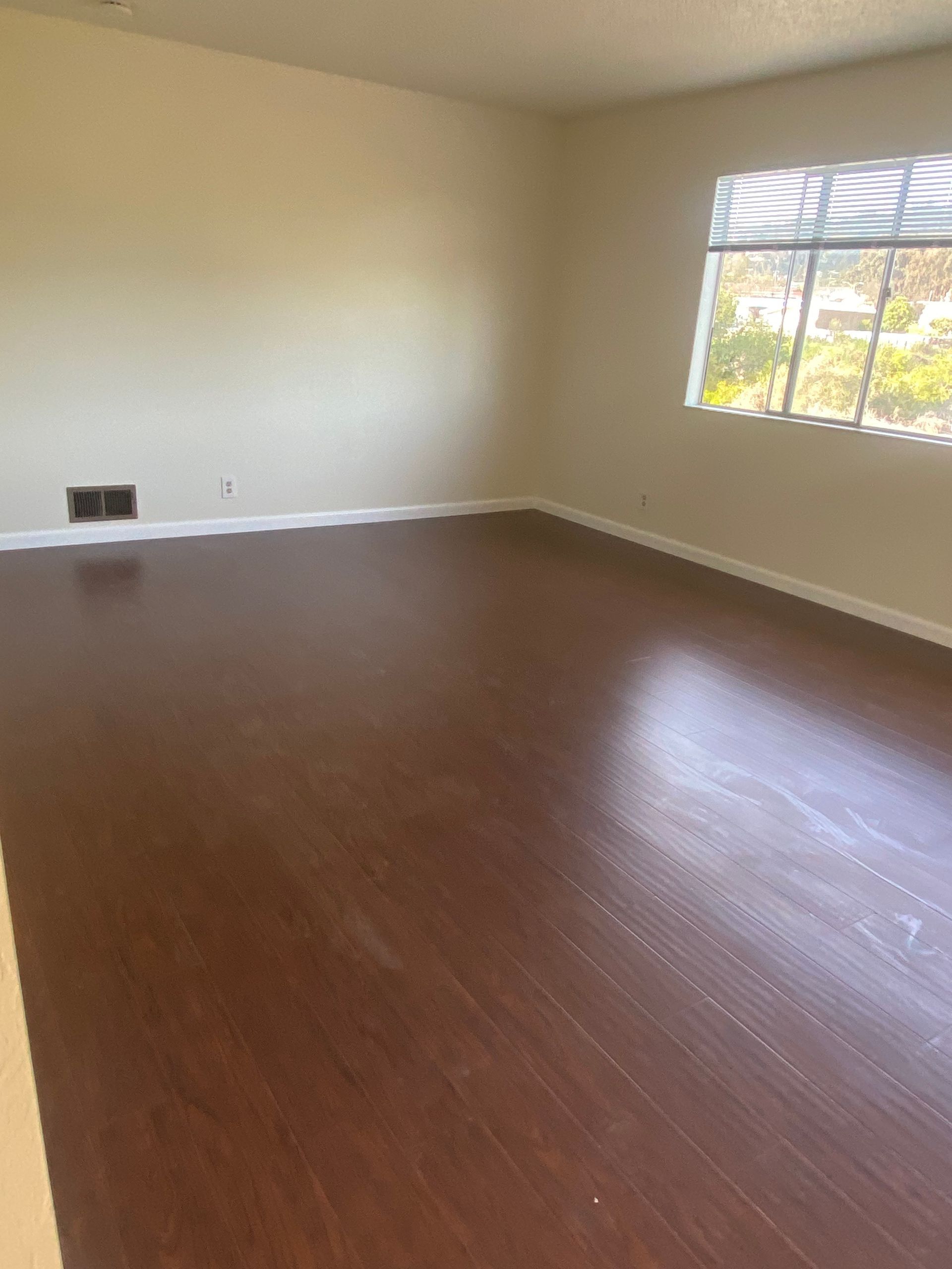 An empty living room with hardwood floors and a window.