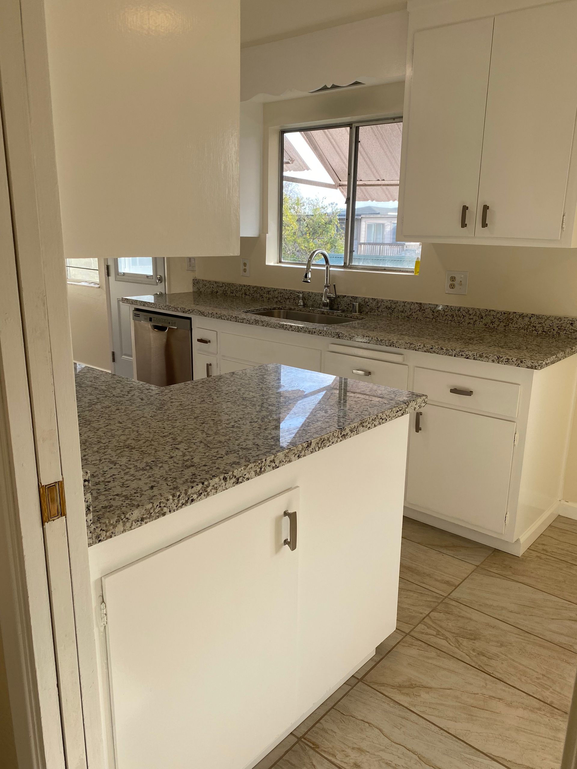 A kitchen with white cabinets and granite counter tops.