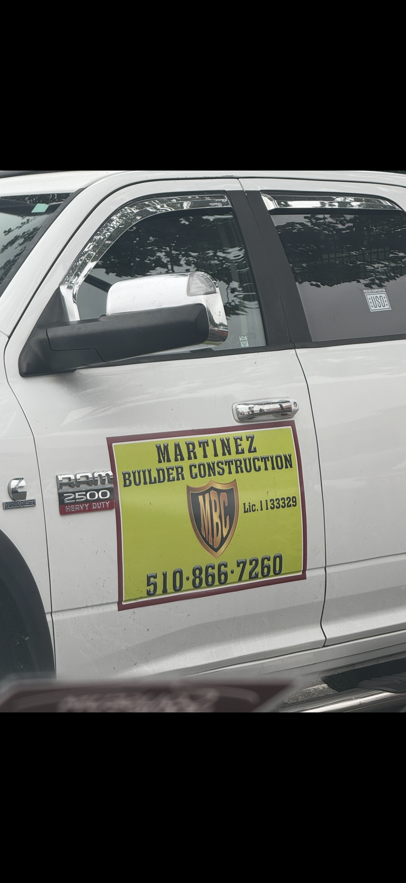 A white truck with a yellow sign on the side that says martial construction