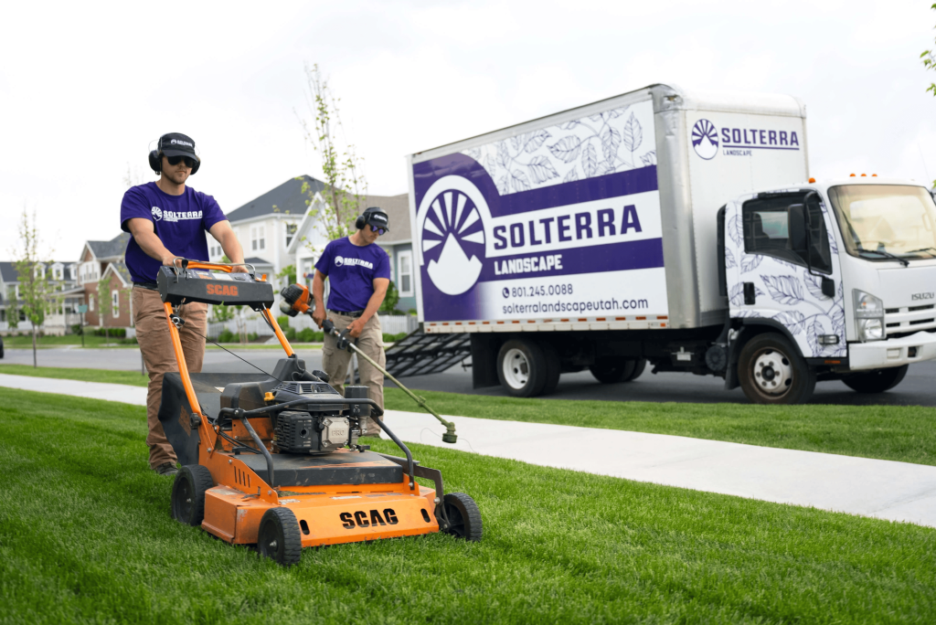 Two men mowing a lawn with truck nearby, promoting Solterra Lubricare.