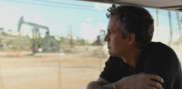 A man in a black shirt is looking out the window of a car.