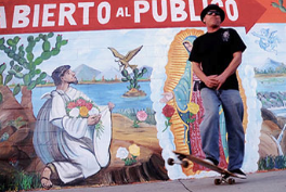 A man standing in front of a mural that says abierto al publico