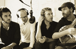A group of men are sitting in front of a microphone and one of them is holding a guitar with the word chris on it