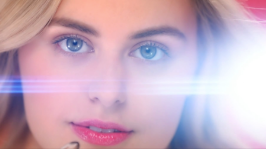 A close up of a woman 's face with a lens flare behind her.