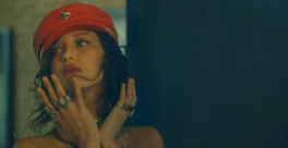 A woman wearing a red hat and rings is looking at herself in the mirror.