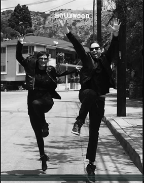 Two people are jumping in the air in front of the hollywood sign