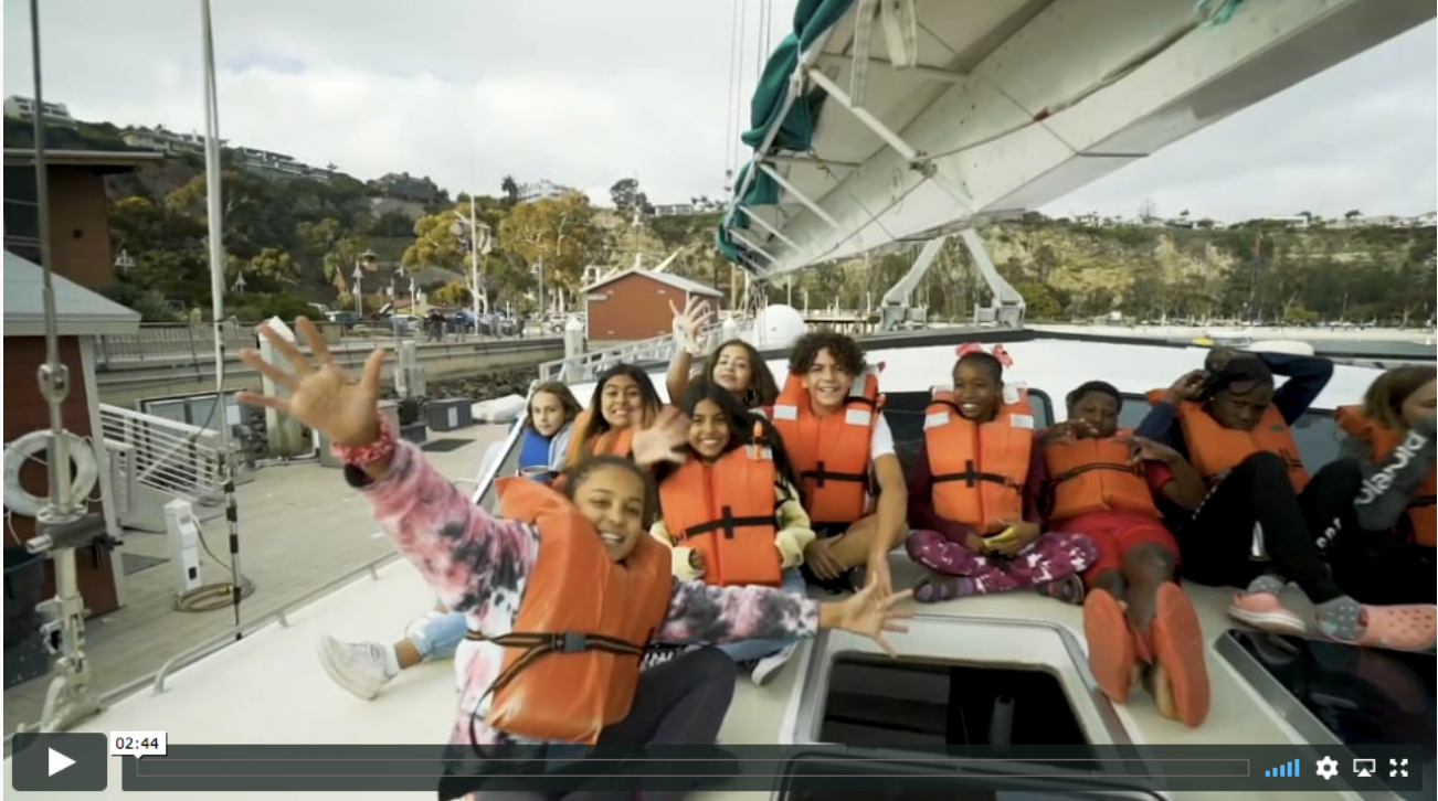 A group of children wearing life jackets are sitting on a boat.